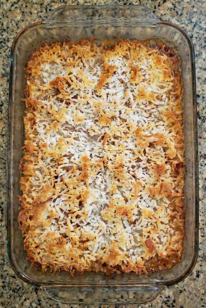 Freshly baked pan of Seven Layer Bars with golden toasted coconut on top. Just out of the oven and ready to cool before slicing.