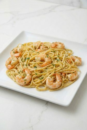 Plate of shrimp scampi with linguine pasta, garnished with parsley. A delicious seafood dinner.