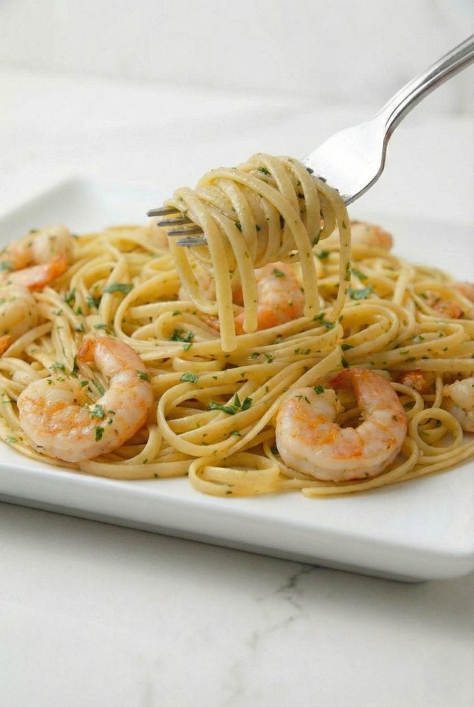 Fork twirling linguine from a plate of shrimp scampi, highlighting the texture and flavor of the finished Shrimp Scampi with Pasta recipe.