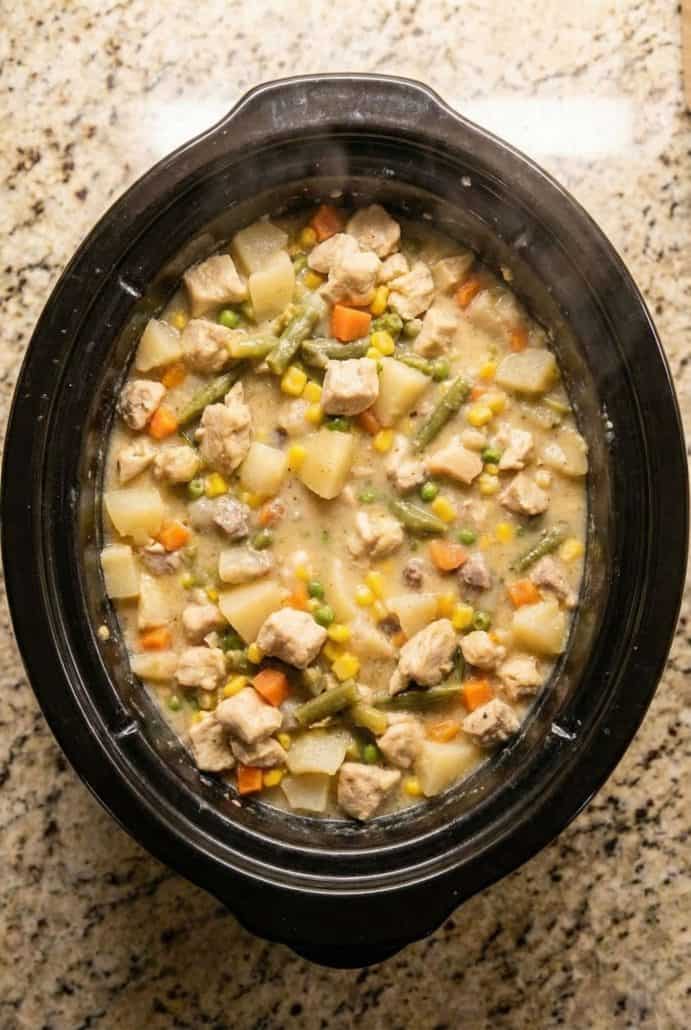 Slow cooker filled with hearty Chicken Pot Pie Stew made with tender chicken, potatoes, carrots, and mixed vegetables.