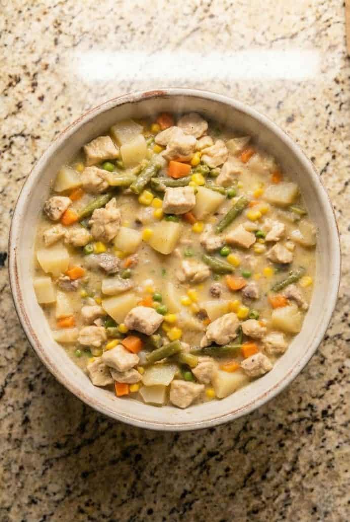 Overhead view of a bowl filled with creamy Chicken Pot Pie Stew made in the slow cooker, loaded with potatoes, chicken, carrots, and mixed vegetables.