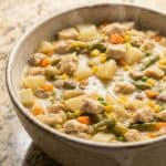 Bowl of creamy Slow Cooker Chicken Pot Pie Stew filled with chicken, potatoes, carrots, and mixed vegetables, served hot as a comforting family dinner.