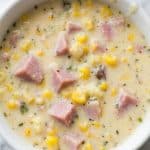 Bowl of creamy slow cooker corn chowder with chunks of ham and sweet corn, ready to serve.