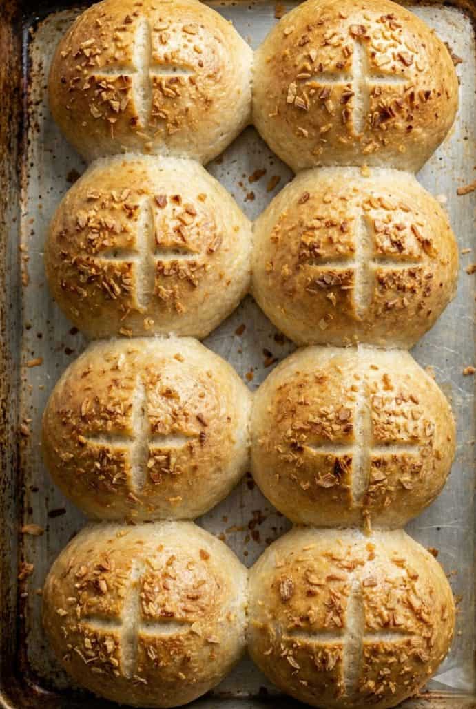 Golden brown onion sandwich rolls fresh out of the oven on a baking sheet.