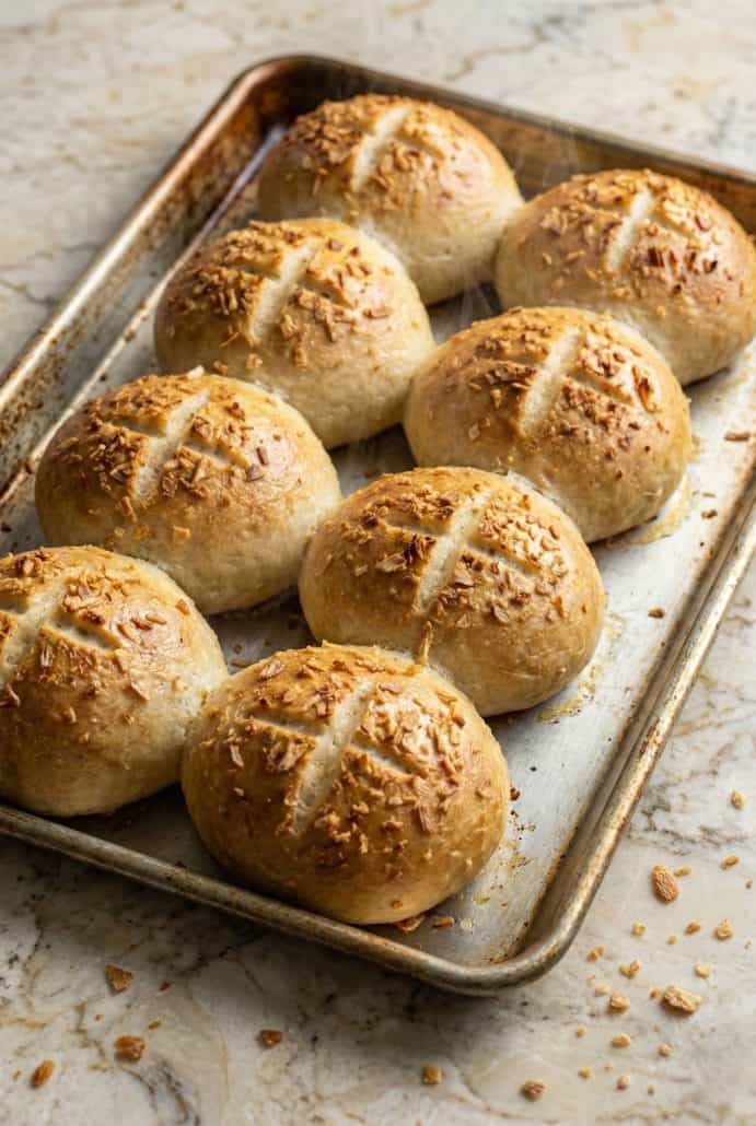 Homemade soft onion rolls cooling on a baking sheet after baking.