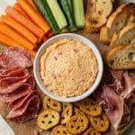 Southern pimento cheese served on a charcuterie board with pretzels, crackers, veggies, and cured meats.
