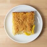 Single serving of baked squash casserole on a white plate, showing the crispy cracker topping and tender squash layers.