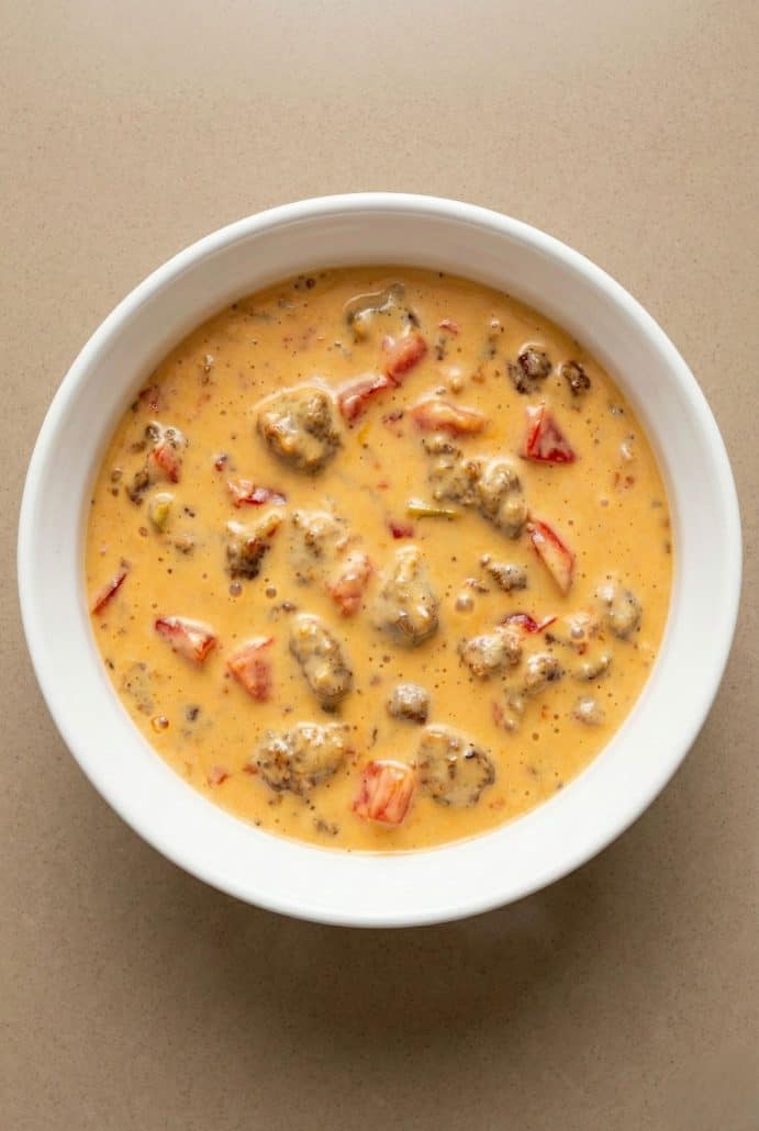 Creamy Velveeta sausage dip with Rotel, served warm in a white bowl.