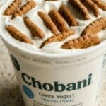 Chobani plain Greek yogurt tub topped with Biscoff cookies pressed into the yogurt.