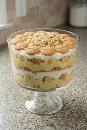 No Bake Banana Trifle Recipe (Creamy, Layered & So Impressive!) Banana trifle layered with pound cake, banana pudding, whipped cream, and vanilla wafers in a glass trifle bowl.
