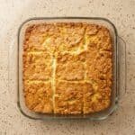 Golden brown butter swim biscuits baked in a square dish and cut into nine pieces, showing the crispy edges and fluffy texture.