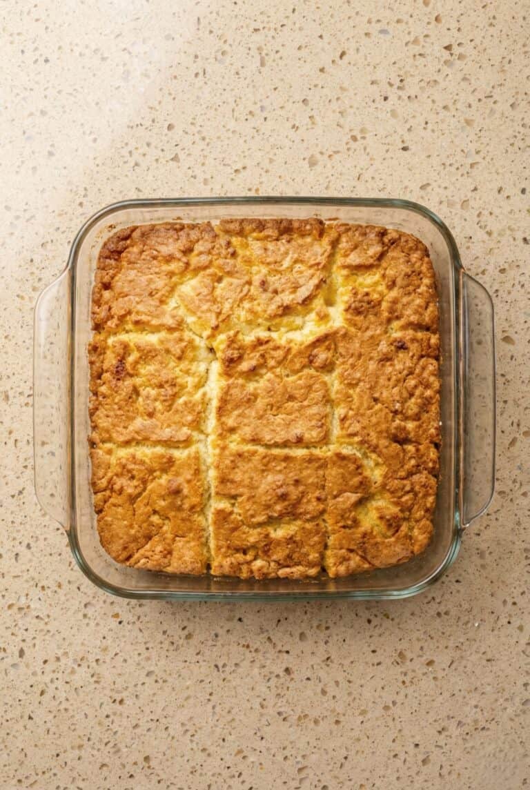 Golden brown butter swim biscuits baked in a square dish and cut into nine pieces, showing the crispy edges and fluffy texture.