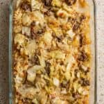 Overhead image of hearty cabbage roll casserole baked in a glass dish, showing tender cabbage, ground beef, and rice in rich tomato sauce.