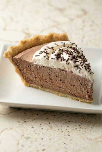 Creamy Chocolate Mousse Pie | Easy No-Bake Dessert Recipe Slice of creamy chocolate mousse pie with whipped topping and chocolate curls on a white plate, highlighting the rich and fluffy texture.