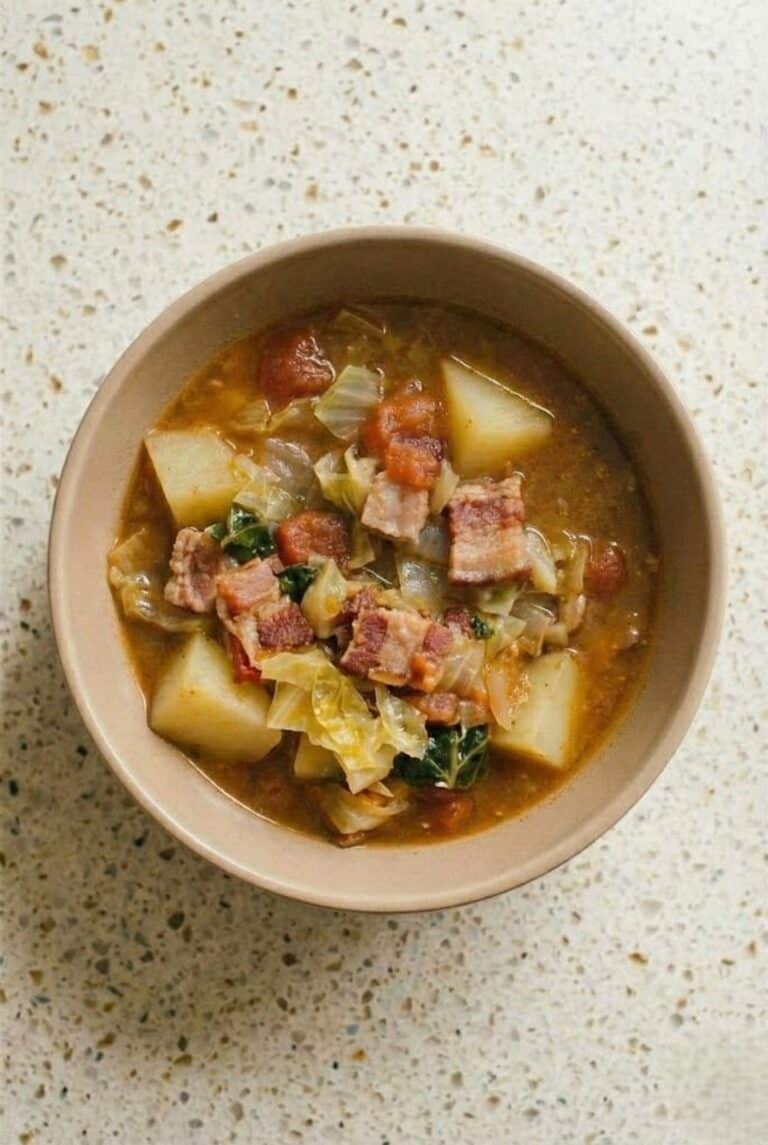 Top view of homemade Irish bacon and cabbage soup in a bowl, filled with tender potatoes, diced bacon, tomatoes, and fresh cabbage.