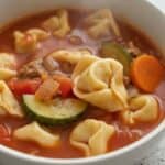 Bowl of Italian sausage tortellini soup with carrots and zucchini.