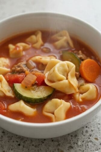 Bowl of Italian sausage tortellini soup with carrots and zucchini.