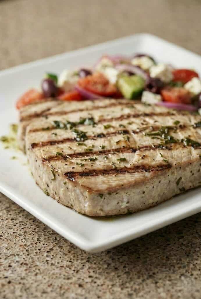 Side view of a perfectly grilled marinated tuna steak with bold grill marks.