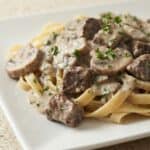 Creamy slow cooker beef stroganoff served over egg noodles, topped with tender beef chunks and sliced mushrooms in a rich mushroom sauce.