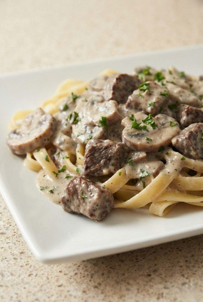 Creamy slow cooker beef stroganoff served over egg noodles, topped with tender beef chunks and sliced mushrooms in a rich mushroom sauce.