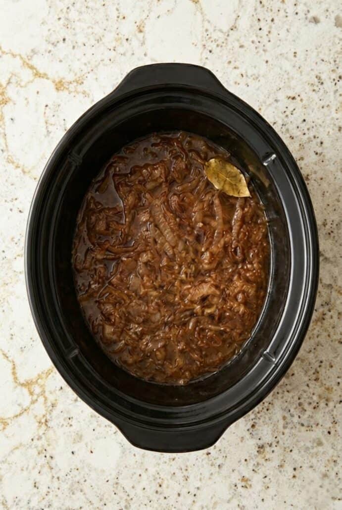 Slow cooker filled with deeply caramelized onions simmering in rich broth, the flavorful base for homemade French onion soup.