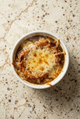 Cheesy French Onion Soup Slow Cooker Recipe Close-up of Slow Cooker French Onion Soup in a ramekin with deeply caramelized onions and a golden, bubbly cheese topping.
