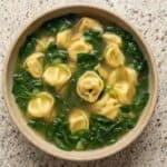 Bowl of spinach tortellini soup with cheese-filled tortellini and fresh spinach in a light broth.