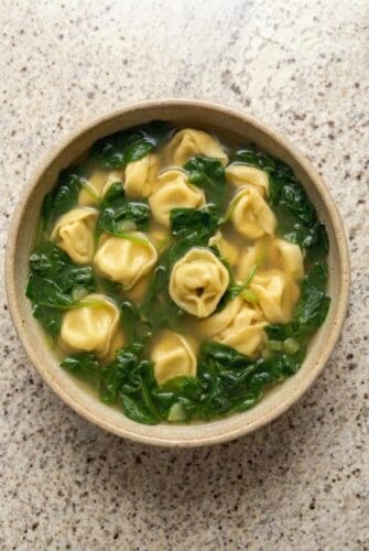 Bowl of spinach tortellini soup with cheese-filled tortellini and fresh spinach in a light broth.