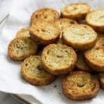 Crispy air fryer bagel chips seasoned with garlic and herbs, served on a paper towel-lined plate.