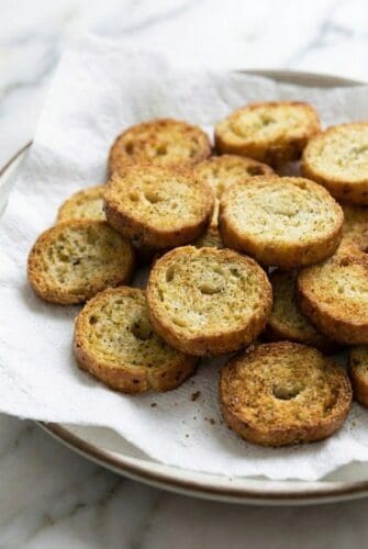 Air Fryer Bagel Chips Recipe Crispy air fryer bagel chips seasoned with garlic and herbs, served on a paper towel-lined plate.