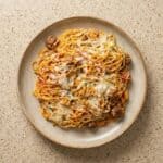 Plate of cheesy baked spaghetti with meat sauce, served hot and ready to enjoy.