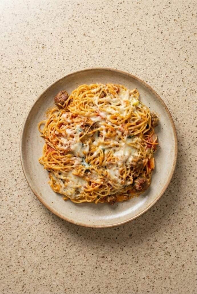 Plate of cheesy baked spaghetti with meat sauce, served hot and ready to enjoy.