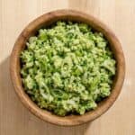 A wooden bowl filled with TikTok Green Goddess Salad, featuring finely chopped cabbage, cucumbers, and scallions tossed in a creamy green dressing.