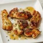 Pan-seared halloumi slices drizzled with hot honey glaze and garnished with thyme on a white plate.