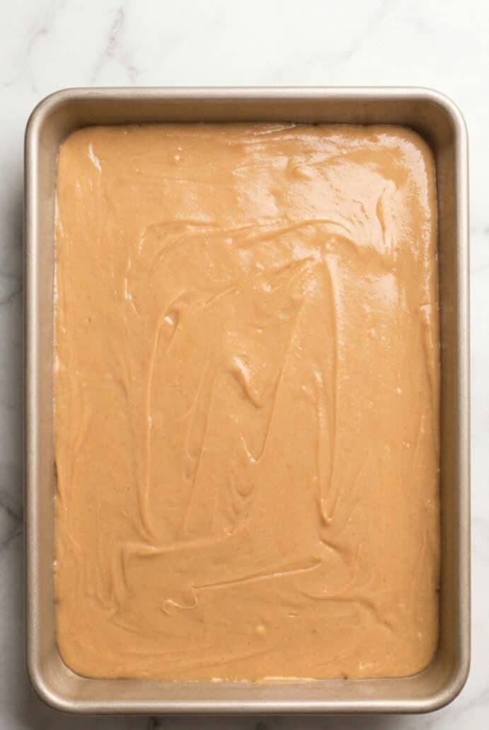 Top view of freshly made peanut butter fudge spread evenly in a 9x13 baking dish before cutting into squares.