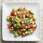 Avocado feta salsa made with chopped tomatoes, avocado, herbs, and crumbled feta served in a white bowl.