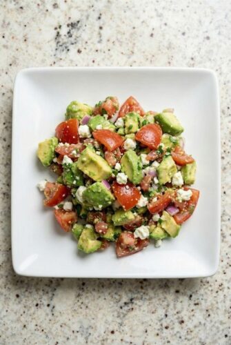 Avocado feta salsa made with chopped tomatoes, avocado, herbs, and crumbled feta served in a white bowl.
