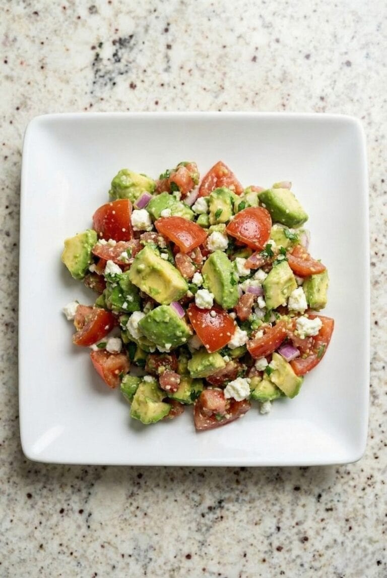 Avocado feta salsa made with chopped tomatoes, avocado, herbs, and crumbled feta served in a white bowl.