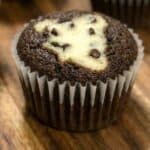 Close-up of a Black Bottom Cupcake with a cream cheese and chocolate chip center, showcasing its signature appearance of chocolate cake with a creamy filling.