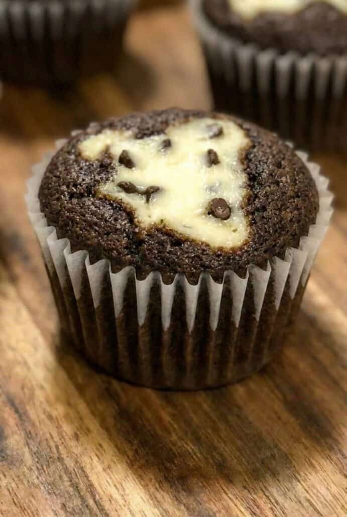 Close-up of a Black Bottom Cupcake with a cream cheese and chocolate chip center, showcasing its signature appearance of chocolate cake with a creamy filling.