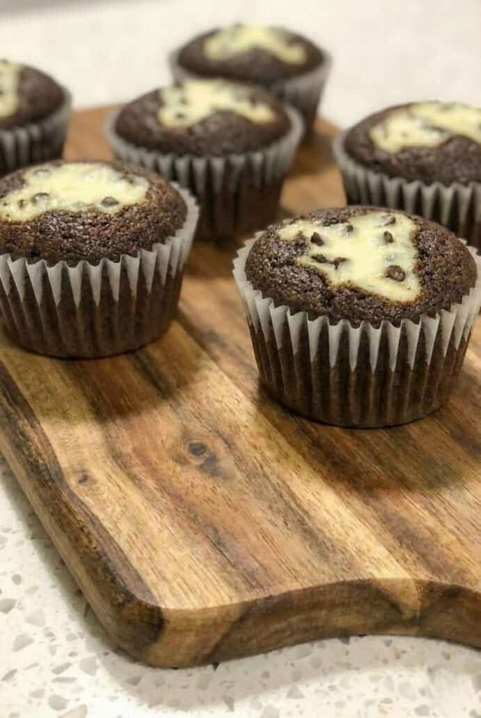 A wooden tray with a close-up of Black Bottom Cupcakes, showcasing their chocolate cake base and creamy chocolate chip-filled centers.