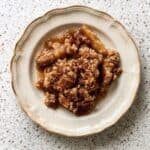 Serving of caramel apple crisp with soft cinnamon apples and crumbly oat topping.