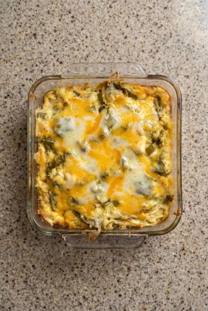 Overhead view of a baked chili relleno casserole in a glass dish topped with melted cheese and poblano peppers.