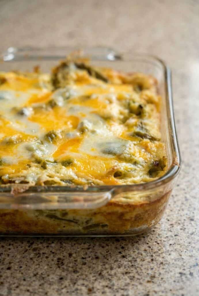 Side view of cheesy chili relleno casserole baked in a glass dish, showing layers of poblano peppers and melted cheese.