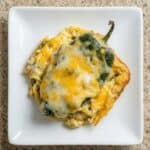 Cheesy chili relleno casserole made with poblano peppers and melted cheese, served on a white plate.