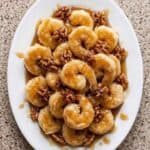 Honey walnut shrimp coated in creamy sauce and topped with candied walnuts, served on a white platter.