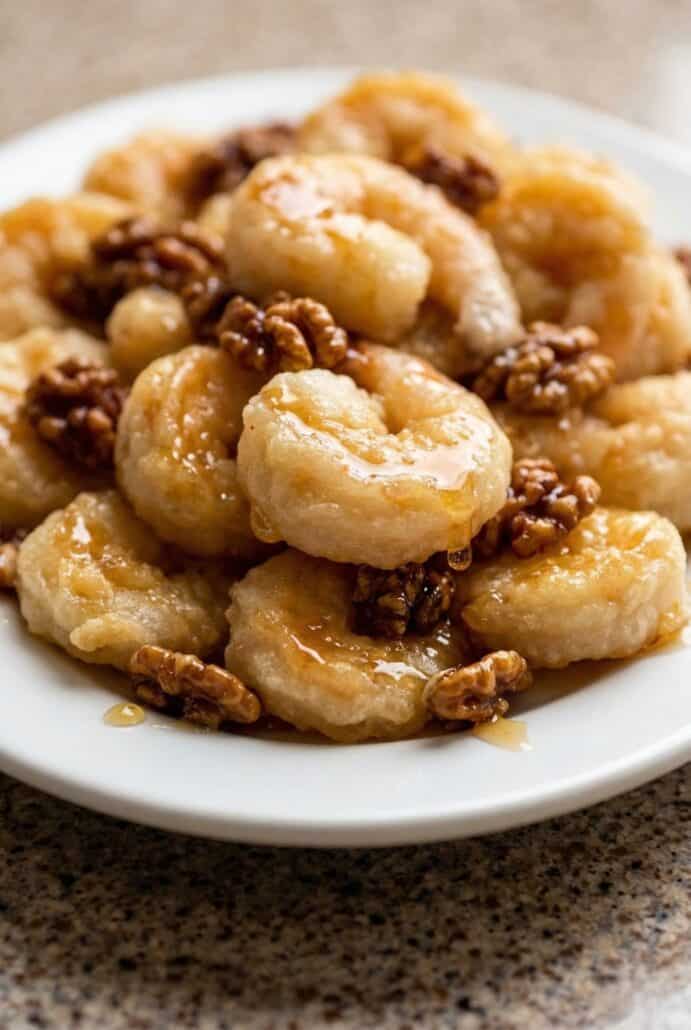 Close-up of crispy honey walnut shrimp coated in creamy honey sauce with candied walnuts.