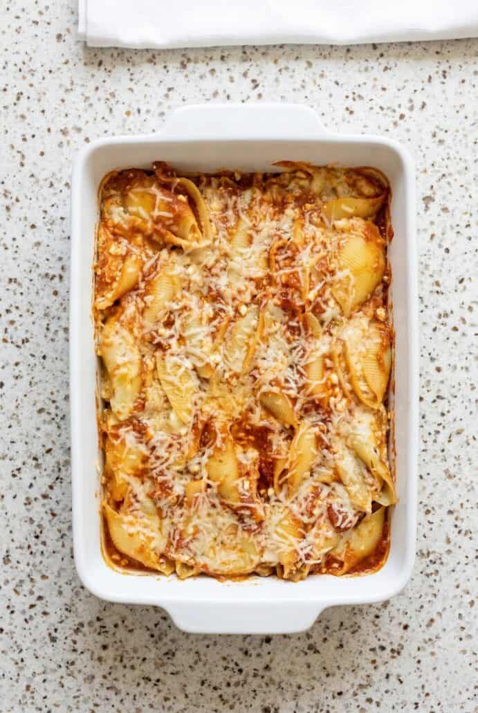 Baking dish filled with golden, bubbling stuffed pasta shells, topped with melted cheese and baked to perfection.