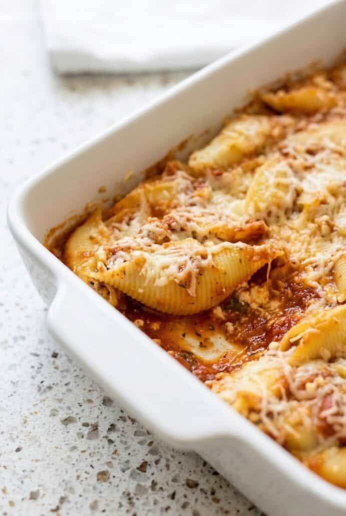 Baking dish with stuffed pasta shells, topped with melted cheese and marinara sauce, showcasing a deliciously baked portion from a Jumbo Stuffed Shells recipe.