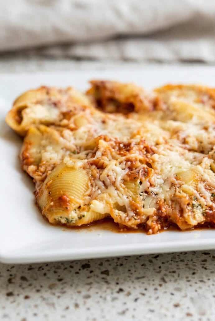 A close-up of a plate with a serving of Jumbo Stuffed Shells, covered with melted cheese and marinara sauce, showcasing a delicious, cheesy, and satisfying Italian dish.